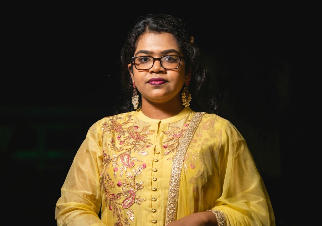 Stunning portrait of a woman in yellow traditional clothing with intricate embroidery and eyeglasses.